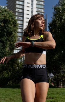Young woman in sportswear jogging in a sunny city park.