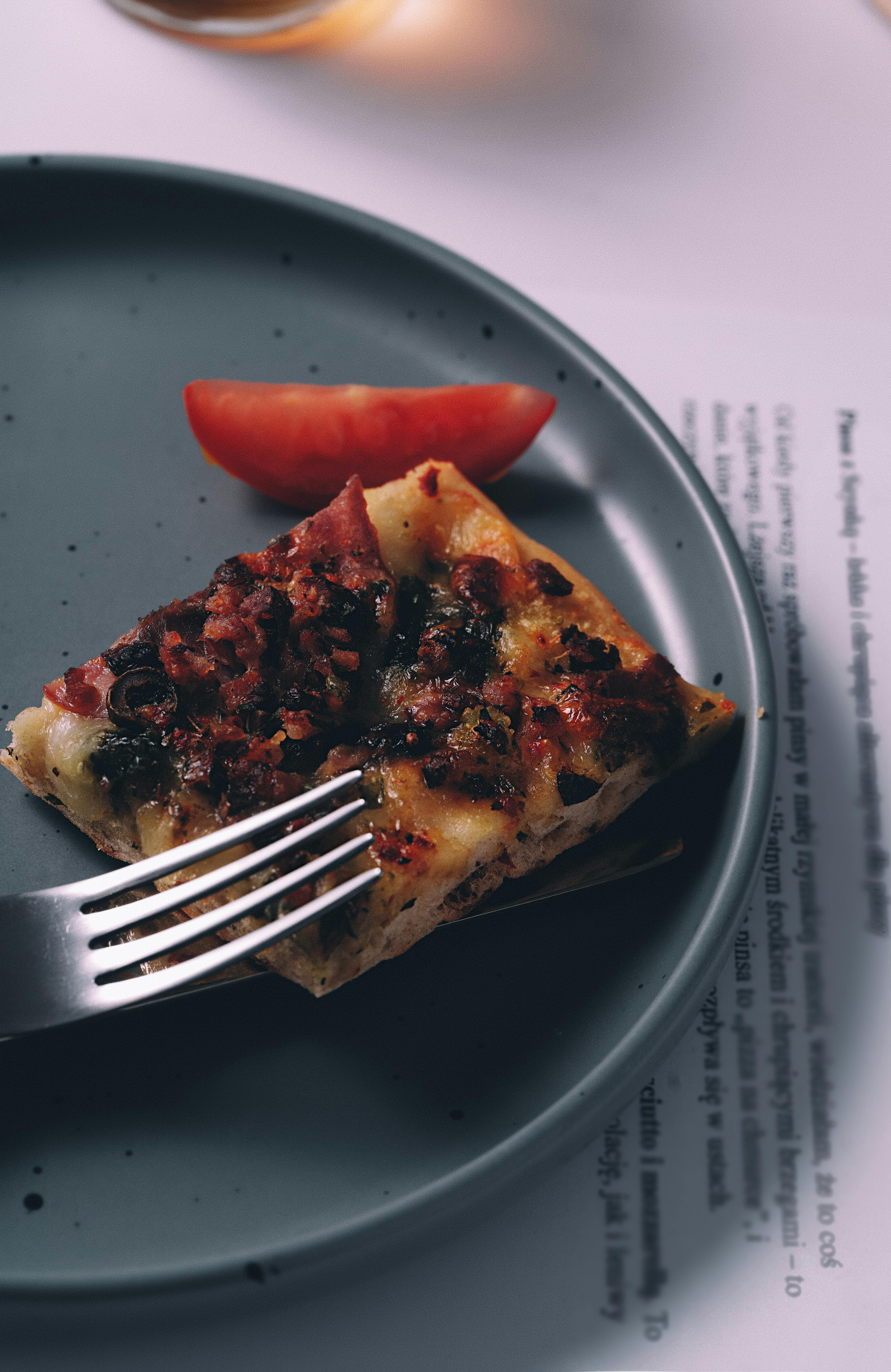 Delicious gourmet pizza slice with toppings on a plate, showcasing fine dining aesthetics.