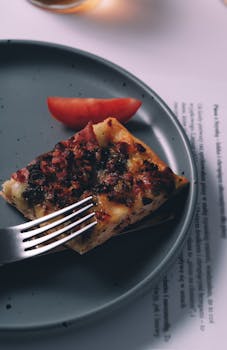 Delicious gourmet pizza slice with toppings on a plate, showcasing fine dining aesthetics.