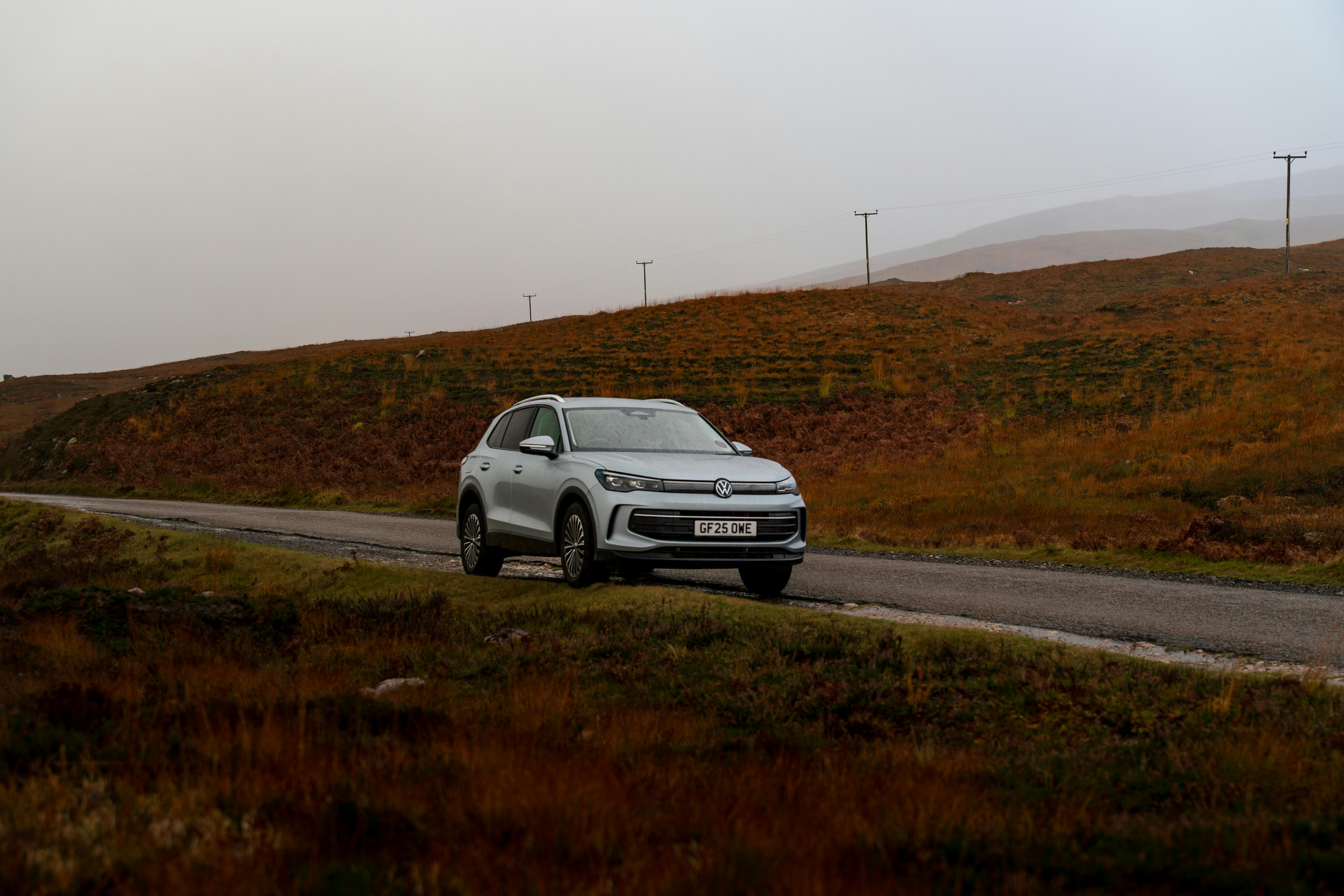 Free A silver SUV traveling on a scenic, remote road in the highlands during autumn. Stock Photo