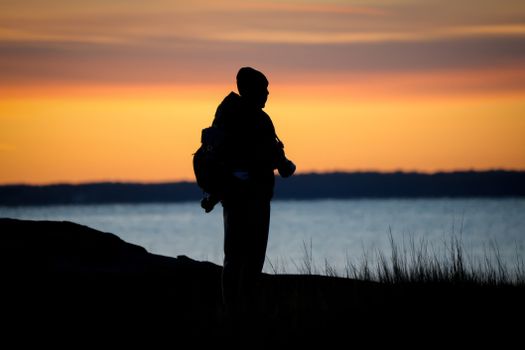 Silhouette of a photographer by the sea capturing the vibrant sunset.