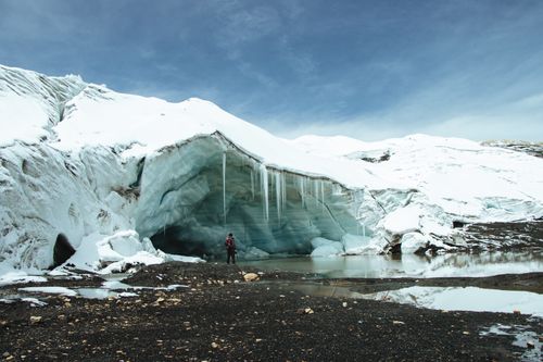 Free A lone hiker stands before the expansive Quelccaya Glacier in Cuzco, Perú, under a clear sky. Stock Photo