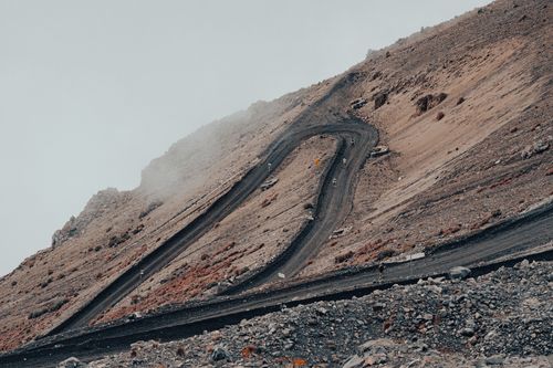 Free A winding road traverses a barren, rocky mountain with fog above. Stock Photo