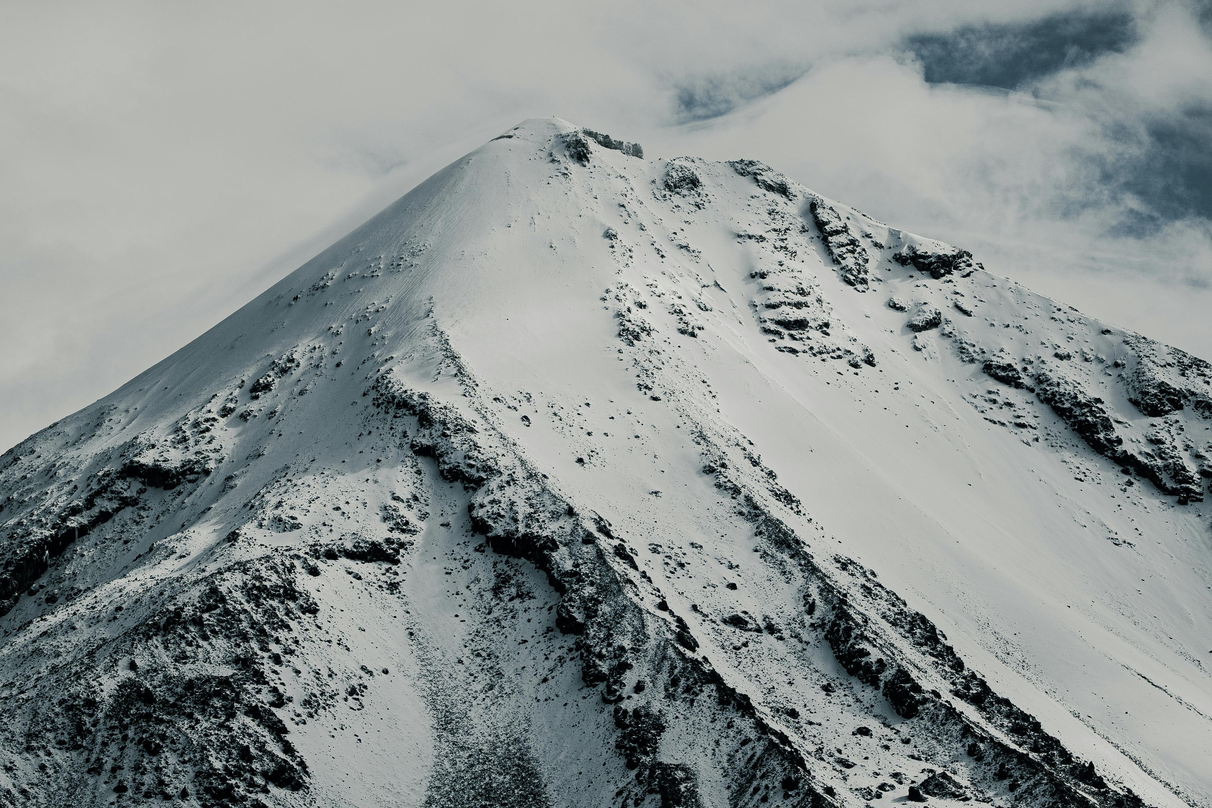 A breathtaking view of a snow-capped mountain peak under cloudy skies, capturing natural beauty.