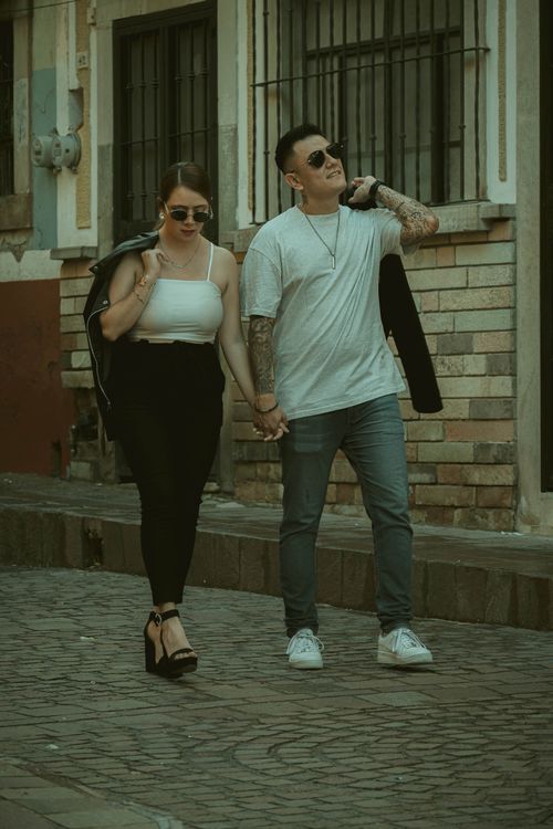 Free Stylish couple holding hands, walking in scenic Guanajuato street with a vintage vibe. Stock Photo