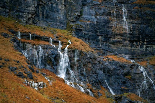 Captivating autumn landscape with a waterfall cascading down a rocky mountain slope.