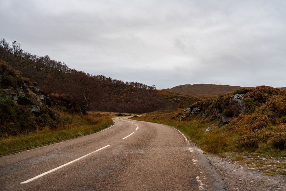 A lonely winding road through the autumnal Scottish Highlands.