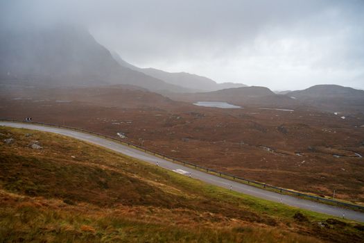A winding road through a misty mountainous landscape on a cloudy day.
