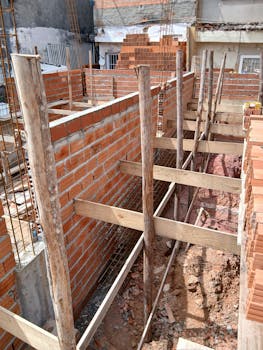 Construction site with brick walls and wooden supports under daylight.