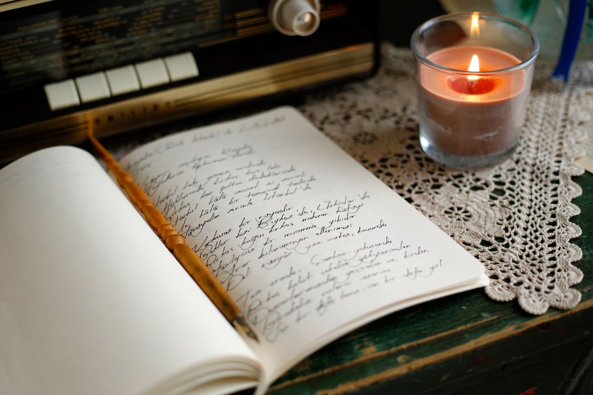 Cuaderno antiguo con anotaciones a mano y una vela encendida