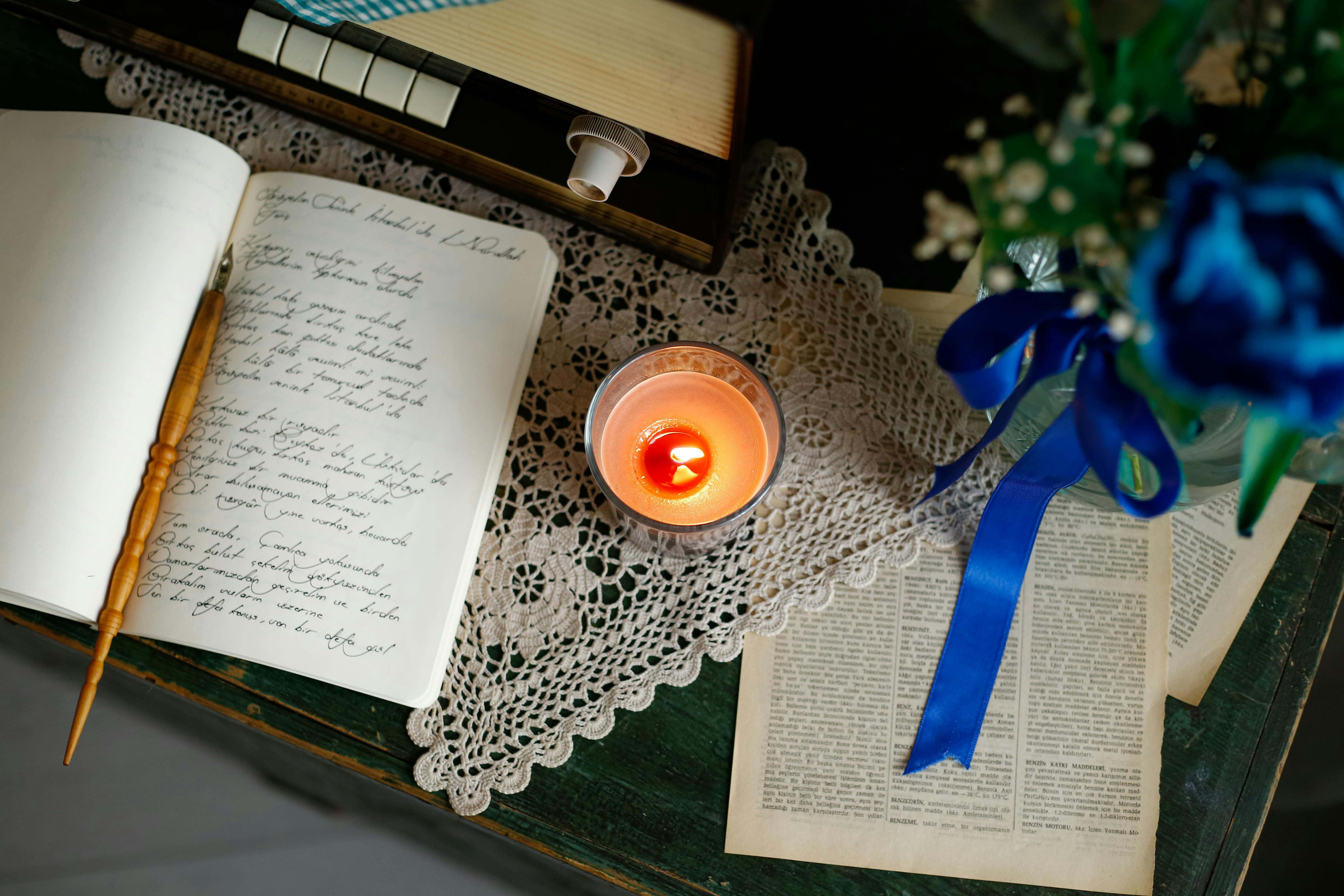 person writing in a journal by candlelight, phone turned face down on a table