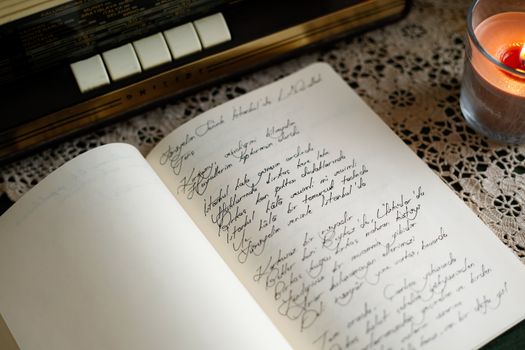 A cozy scene with vintage notebook, handwriting, and candlelight on a lace table.