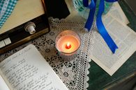 Cozy vintage scene with candlelight, radio, and handwritten manuscript on lace.
