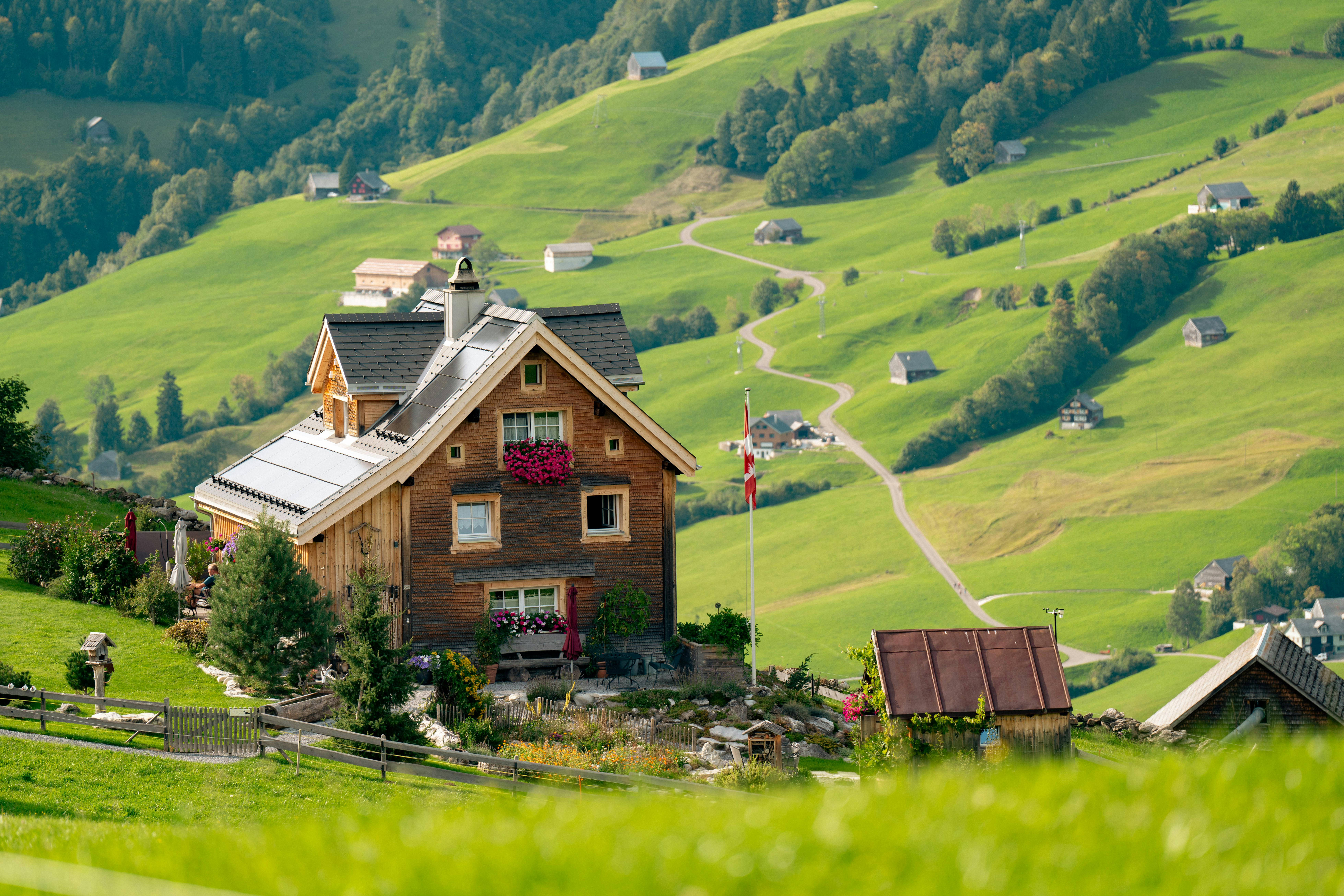 benefits of sustainable tourism for your travel agency clients - Idyllic Swiss chalet surrounded by green rolling hills and scenic mountain views, perfect for travel inspiration.