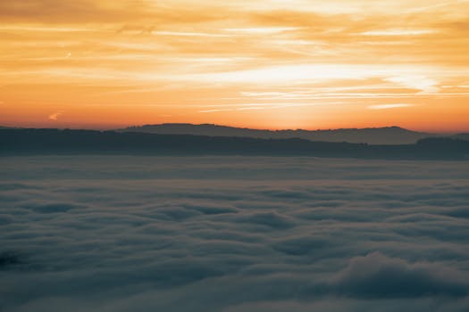 A breathtaking view of a sunset over a cloud-covered mountain range, creating a serene atmosphere.