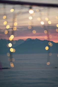 Serene sunset over mountains with bokeh lights adding a dreamy effect.