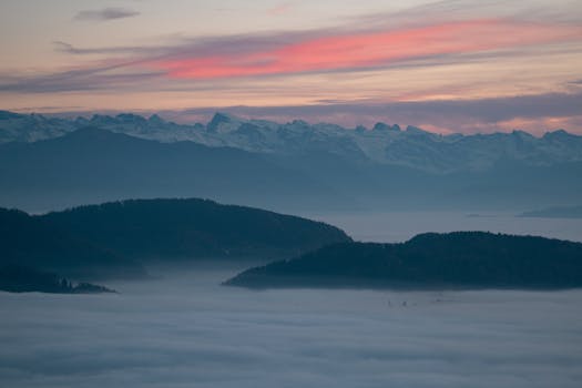 Stunning twilight view of mountains with mist and vibrant sky, perfect for nature and travel themes.