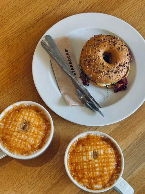 Free Top down view of a bagel with coffee cups on a wooden table, perfect breakfast scene. Stock Photo