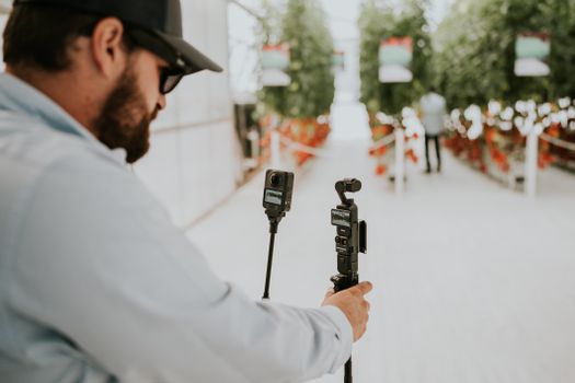 A technician uses cameras to record in a vibrant greenhouse filled with tomato plants.
