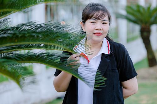 Free Smiling woman behind palm leaves in an outdoor setting, vibrant greenery. Stock Photo
