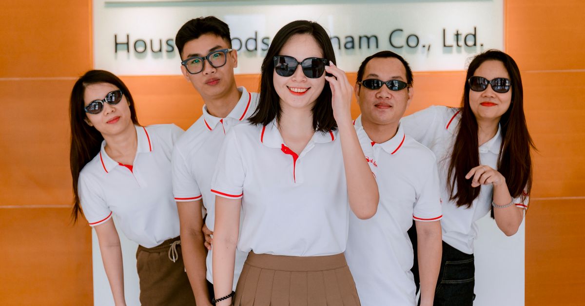 Group of five colleagues wearing polo shirts and sunglasses indoors at company office.