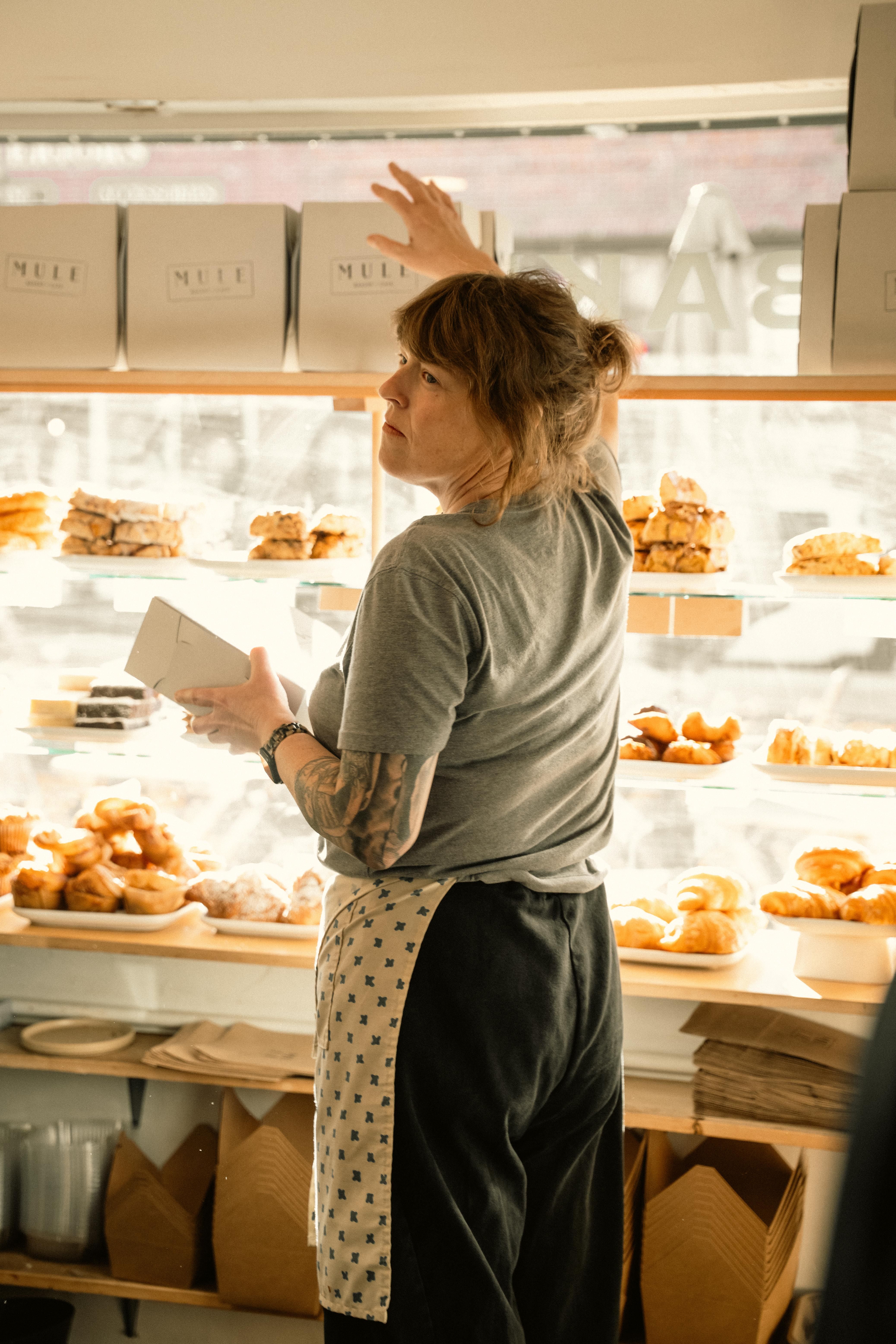 A baker arranging pastries in a cozy bakery