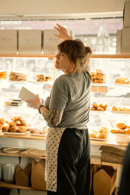 A baker arranging pastries in a cozy bakery