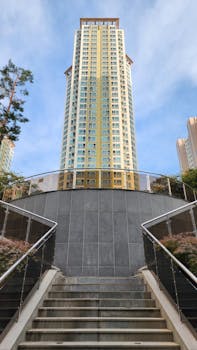 Upward view of a tall modern building with stairs in urban setting.