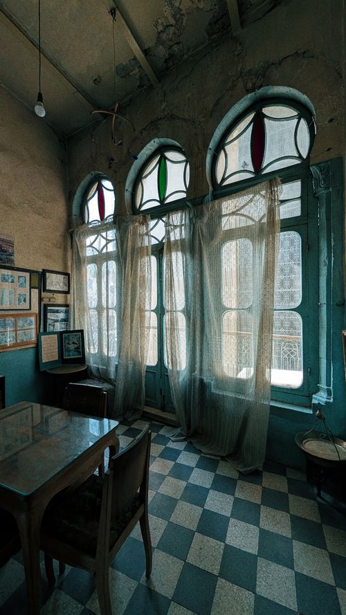 Free Charming vintage room with stained glass windows, checkered floor, and rustic furniture. Stock Photo