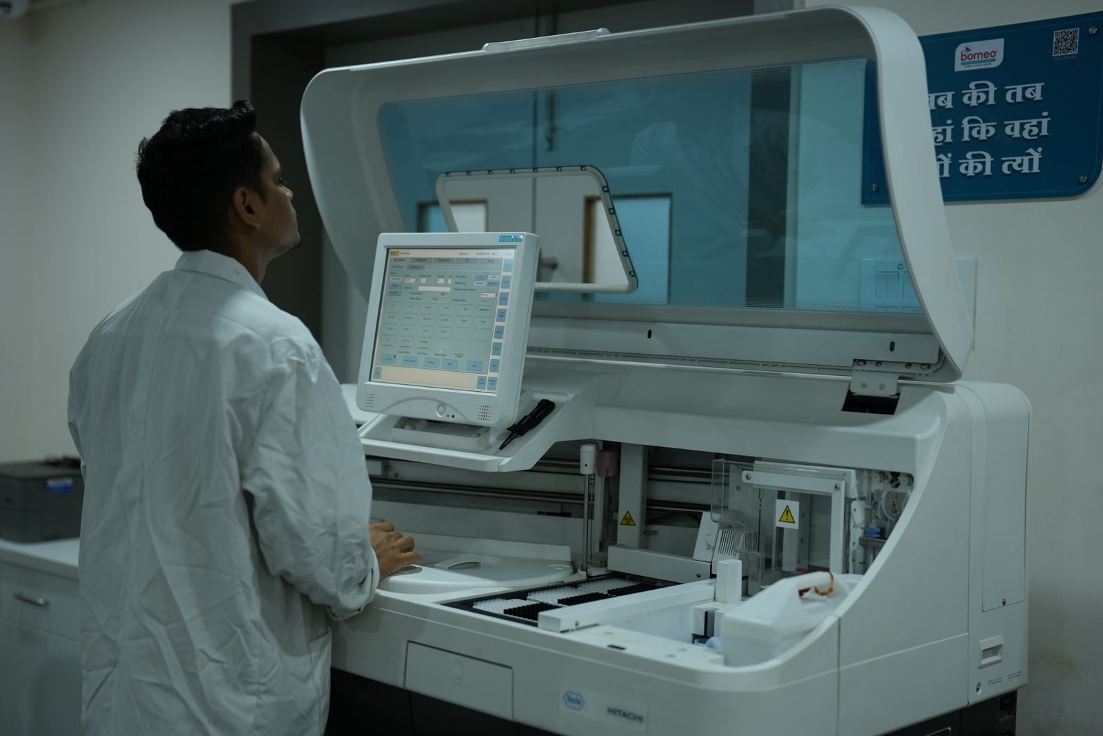 A lab technician operating laboratory analysis equipment in a clean lab