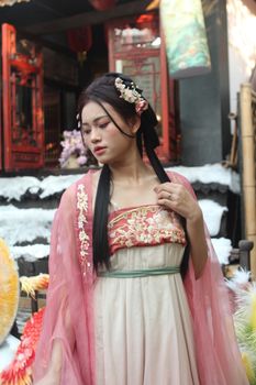 Young woman wearing a traditional Asian dress and floral headpiece outdoors.