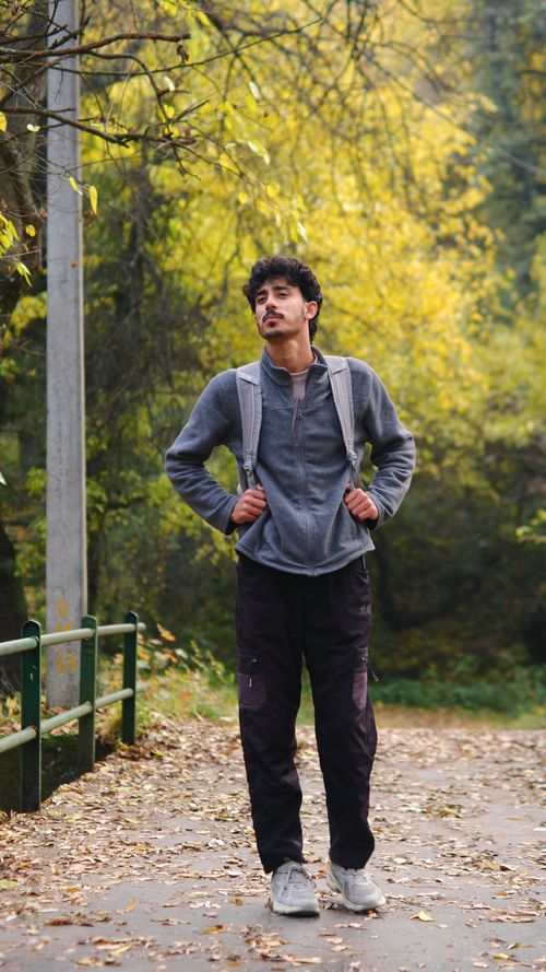 Free Man in casual attire enjoying a peaceful walk through a vibrant fall forest setting. Stock Photo