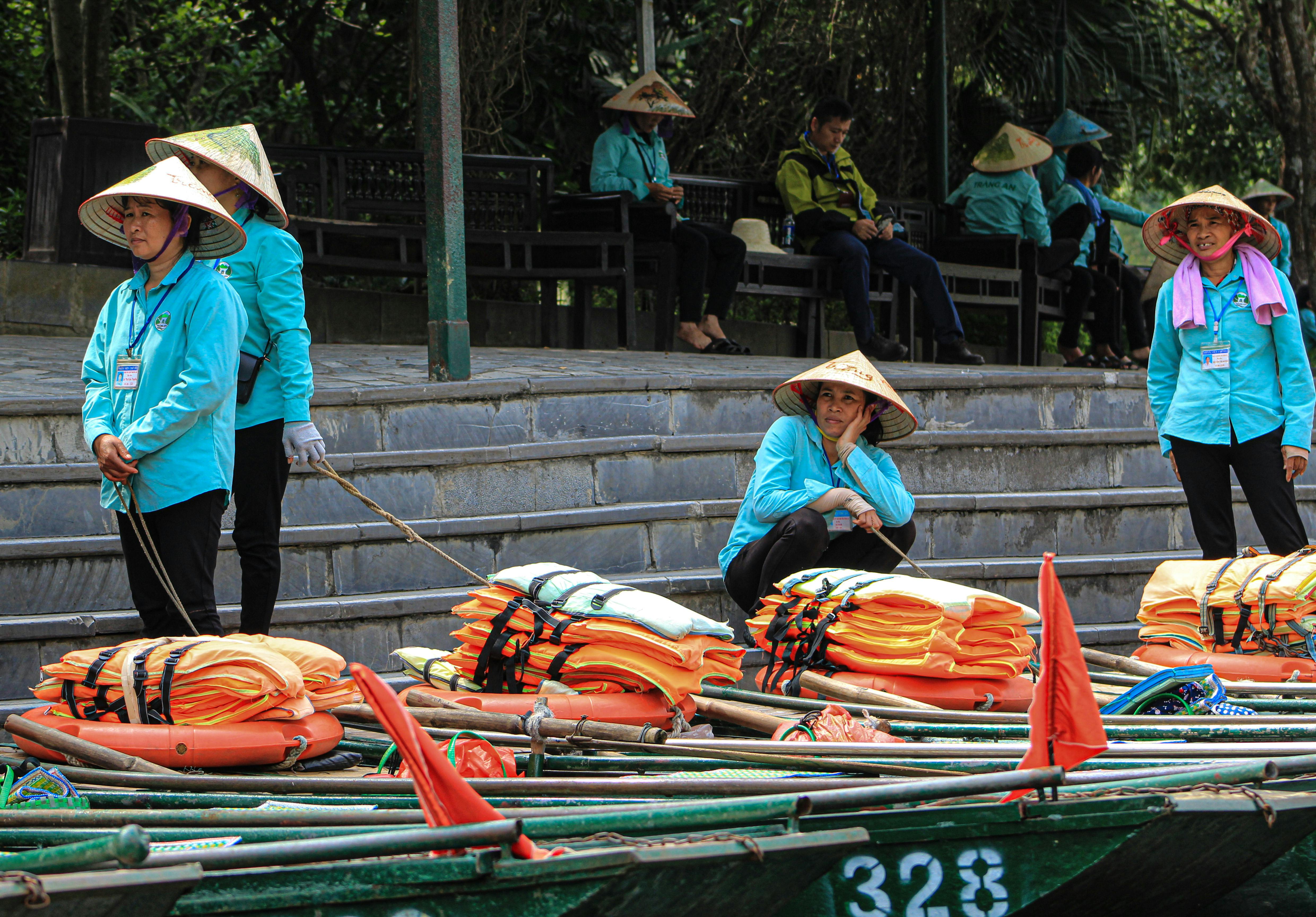 Vietnamese rowers in traditional hats preparing boats for a river tour.