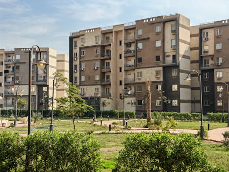 A modern residential building complex with lush greenery and public park.