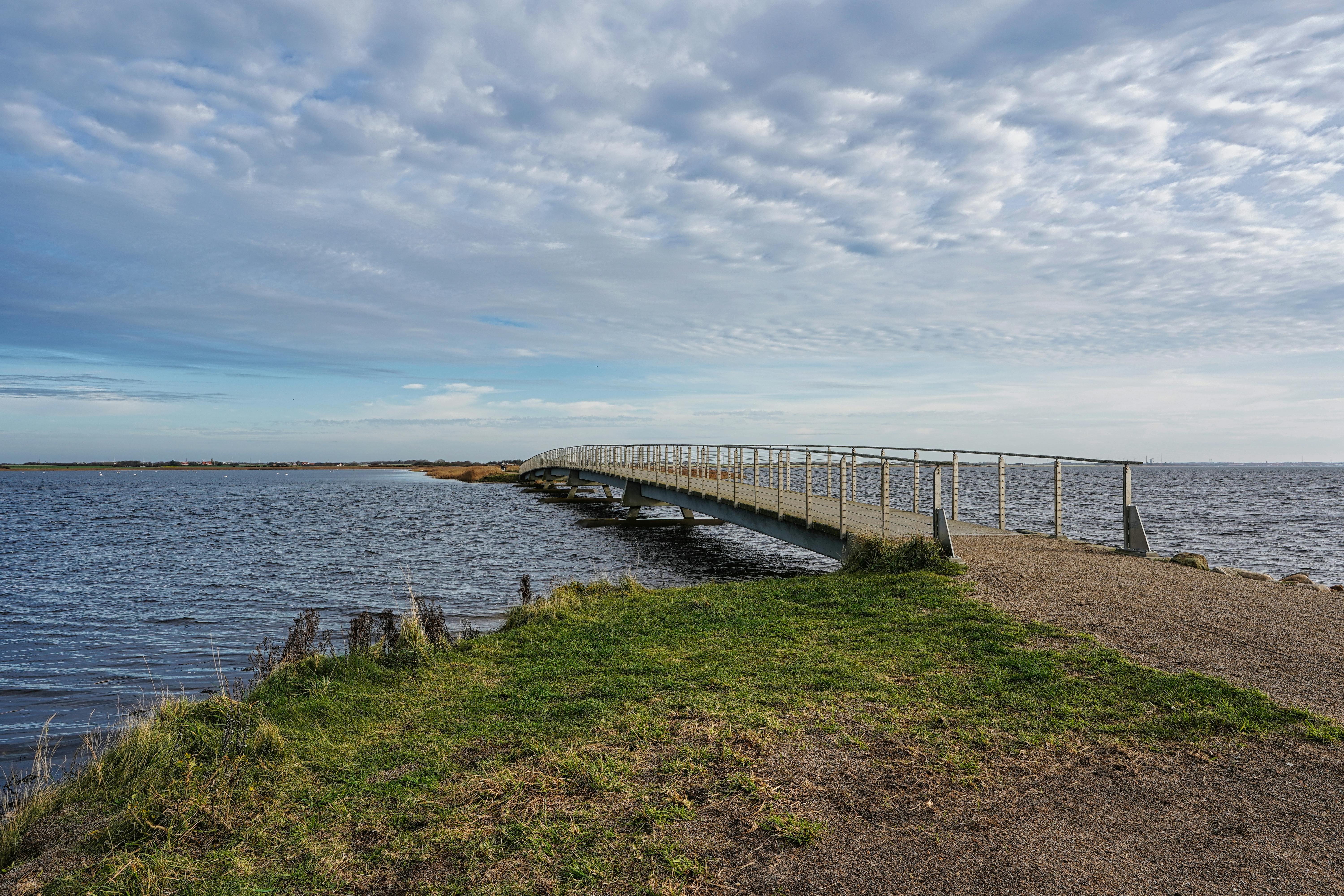 Idyllic bridge over coastal waters in Søndervig, Denmark, capturing a serene, natural landscape.