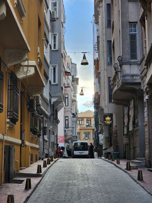 Free Narrow European street flanked by old buildings under a bright sky, showcasing urban charm. Stock Photo