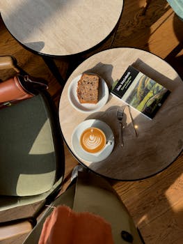 Sunlit cafe table with latte art, cake, and a book in Istanbul, Turkey.