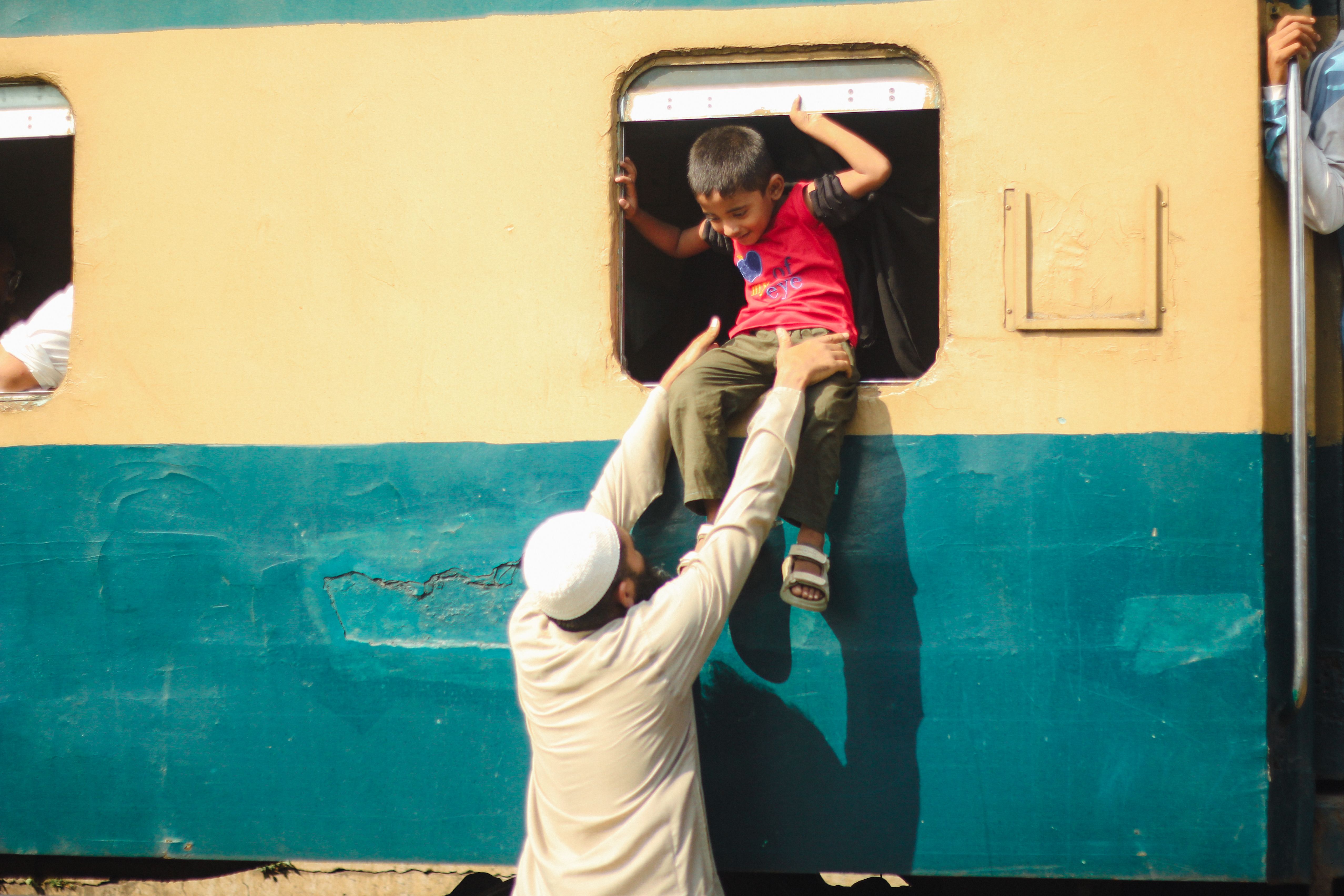 Child being helped onto a train window in Dhaka · Free Stock Photo