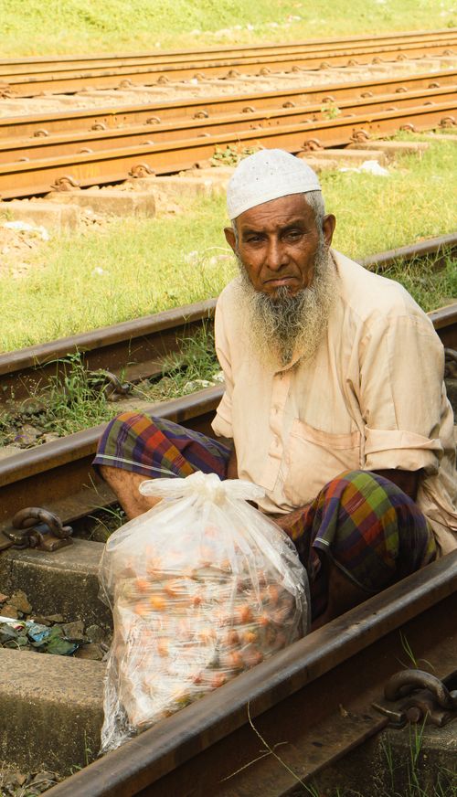 Free Elderly man sitting on railway tracks with a bag. Bright daylight outdoor scene. Stock Photo