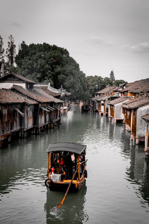 Free Charming boat glides through a historic Chinese water town, surrounded by vintage architecture. Stock Photo