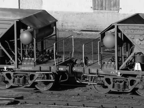 Monochrome close-up of two connected industrial train cars in a rail yard.