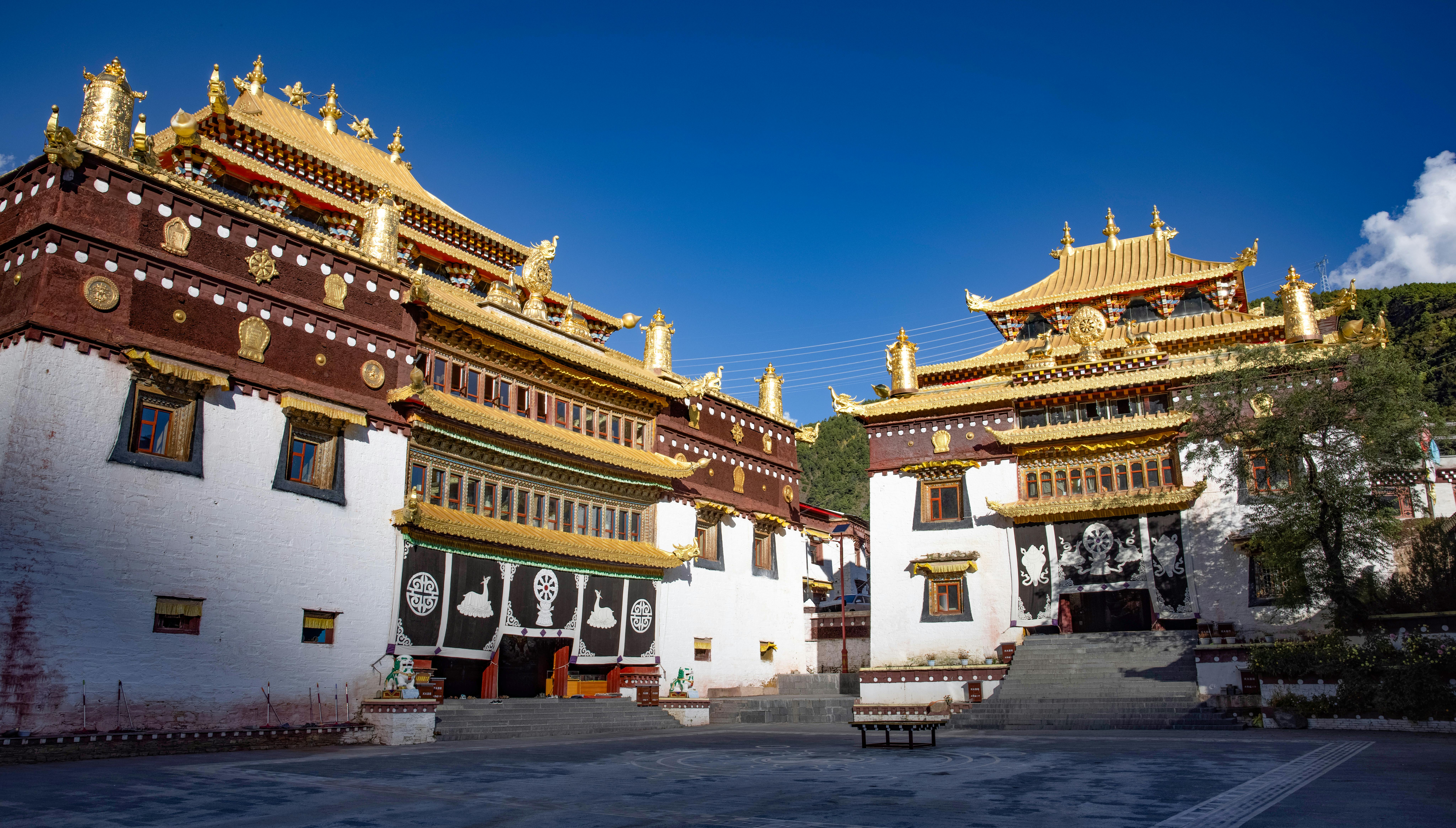 Tashilhunpo Monastery golden spires at sunrise with prayer flags fluttering against Himalayan backdrop in Shigatse Tibet