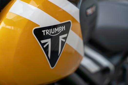 Detailed view of a yellow Triumph motorcycle fuel tank showcasing its logo.