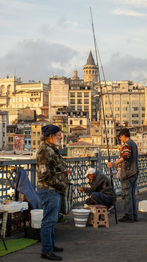 Free Fishermen with fishing rods enjoy the evening on Galata Bridge, Istanbul, with the Galata Tower in the background. Stock Photo