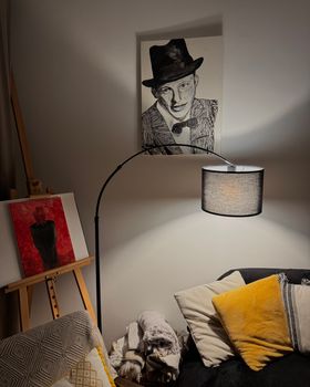 A cozy corner with artistic portraits and warm yellow cushions under soft lighting.