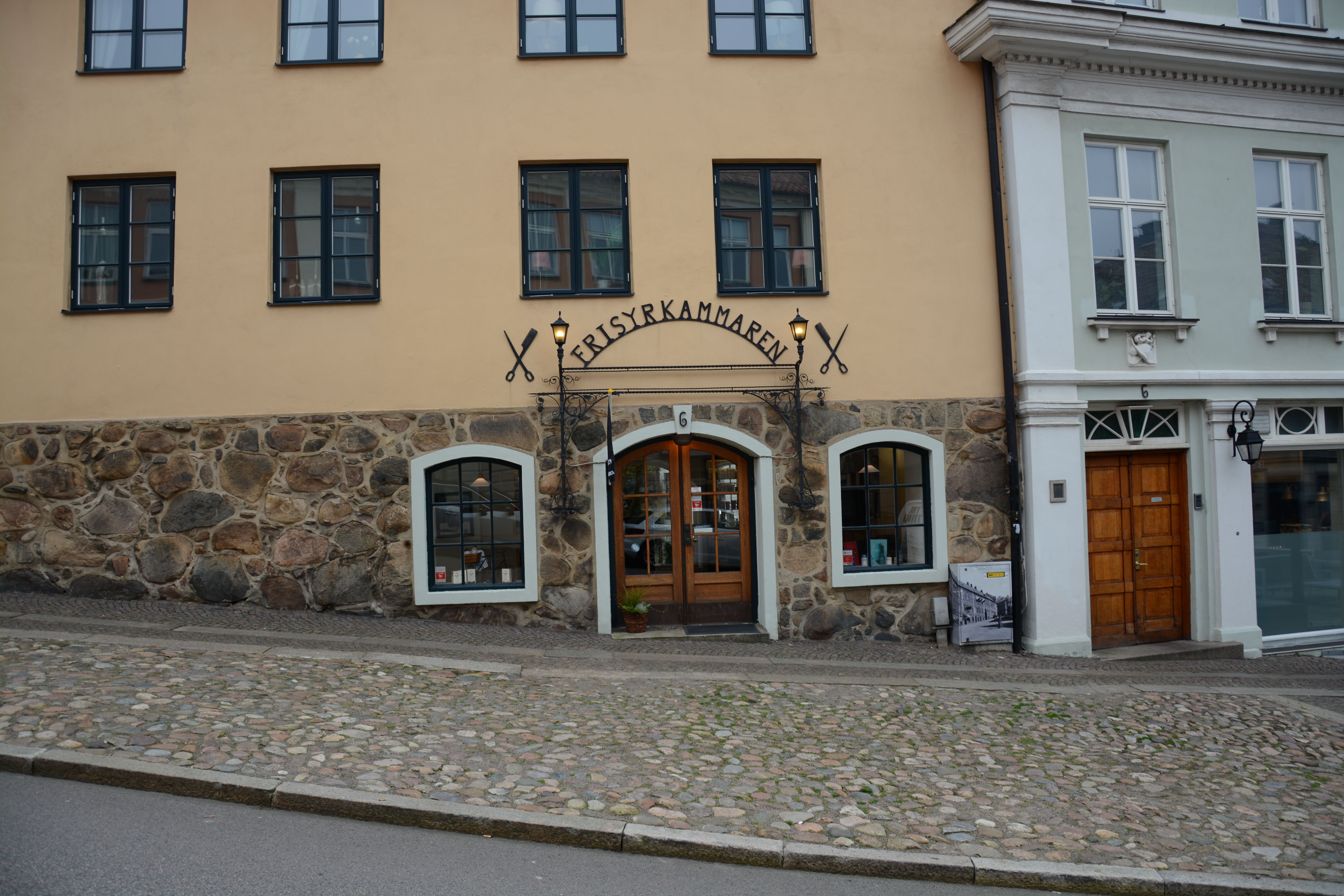 Quaint European barber shop exterior with cobblestone street and historic architecture.