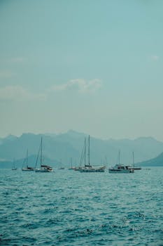 A serene view of yachts sailing on the Aegean Sea with mountainous backdrop.