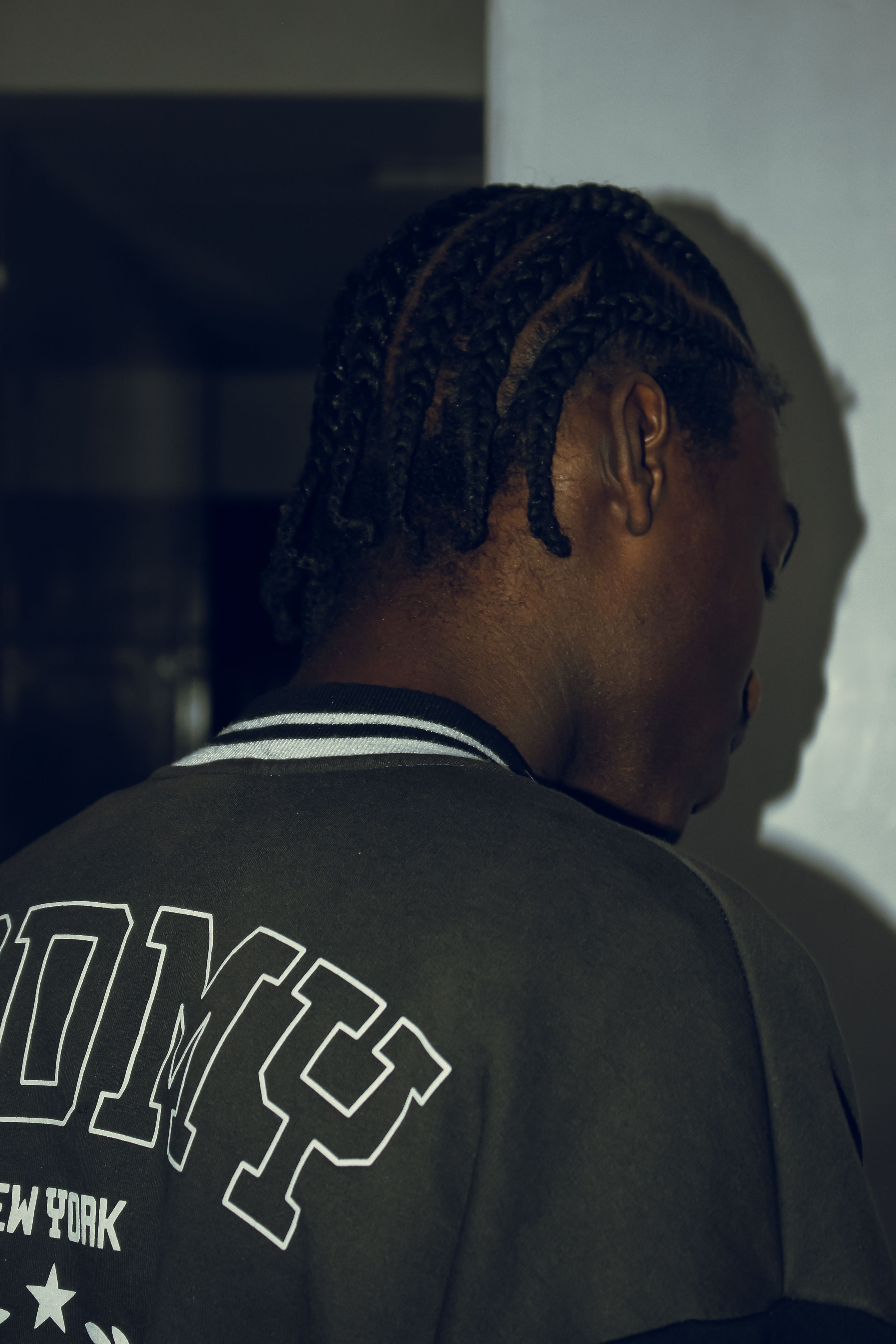 Stylish portrait of a young adult in casual fashion with braided hair, creating a moody and introspective atmosphere.