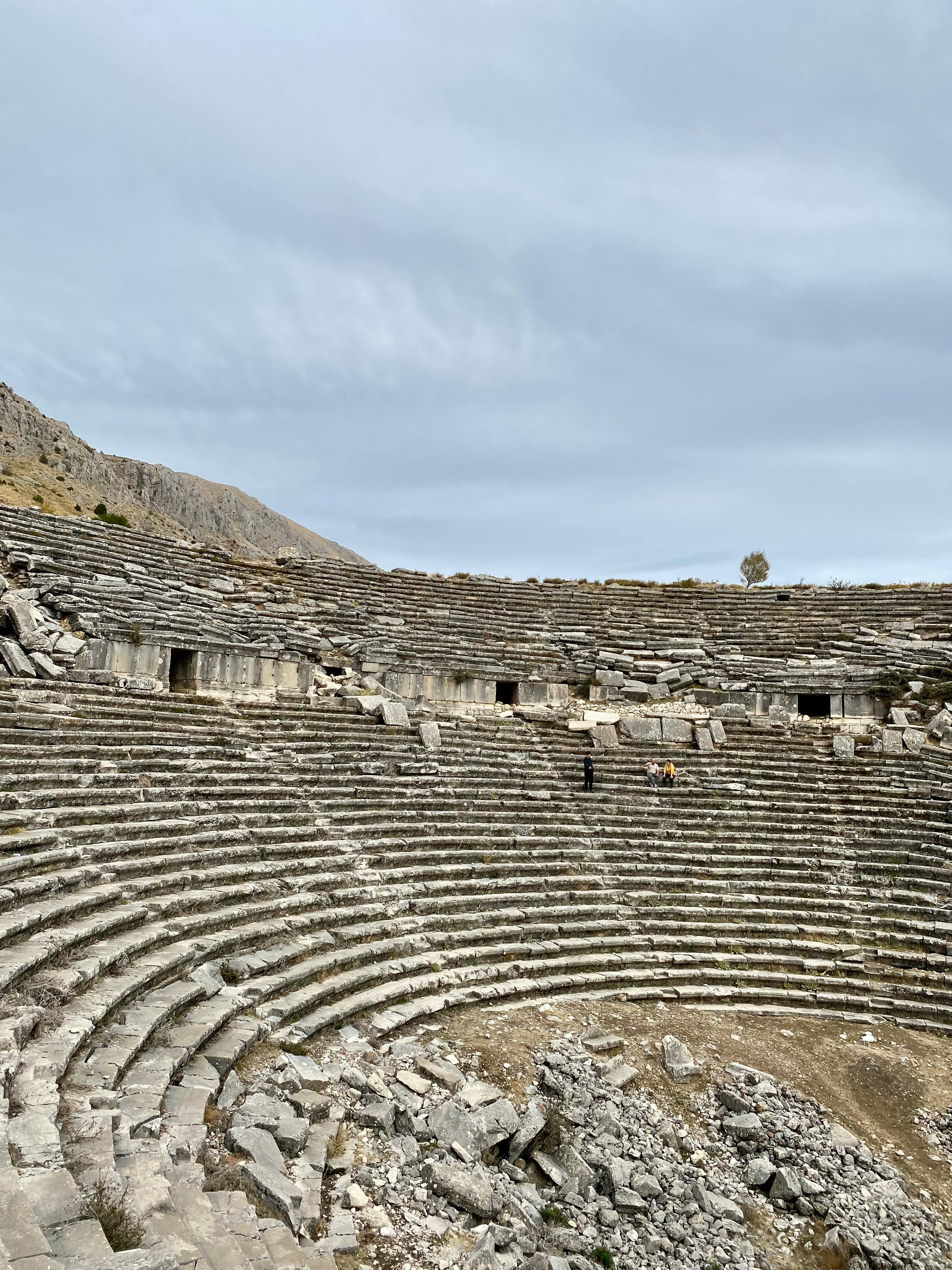 Ücretsiz Kemerli ve bulutlu gökyüzü fonlu tarihi taş amfi tiyatro. Stok Fotoğraflar