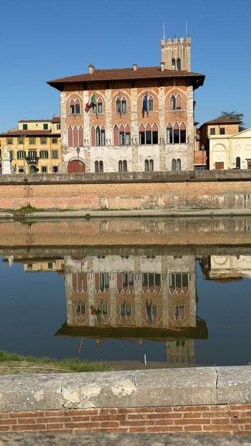 Free Riverside view of a historic Italian building with its reflection in the water. Stock Photo
